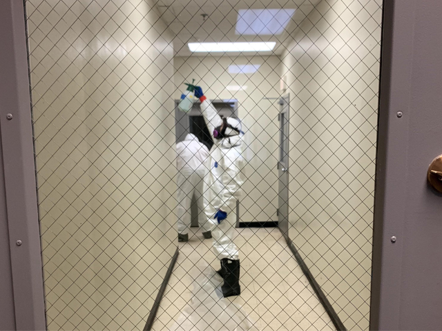 Far spraying disinfectant in hallway