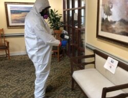 Cleaner in hazmat suit performing COVID-19 disinfection